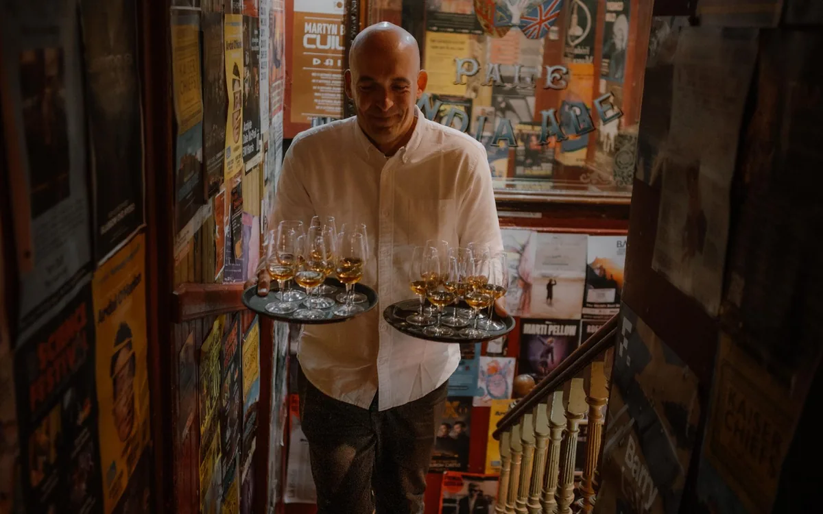 A wooden pub table set with whiskey glasses and a water jug