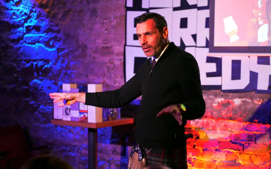 A comedy whiskey tasting room with a performer and a table of glasses