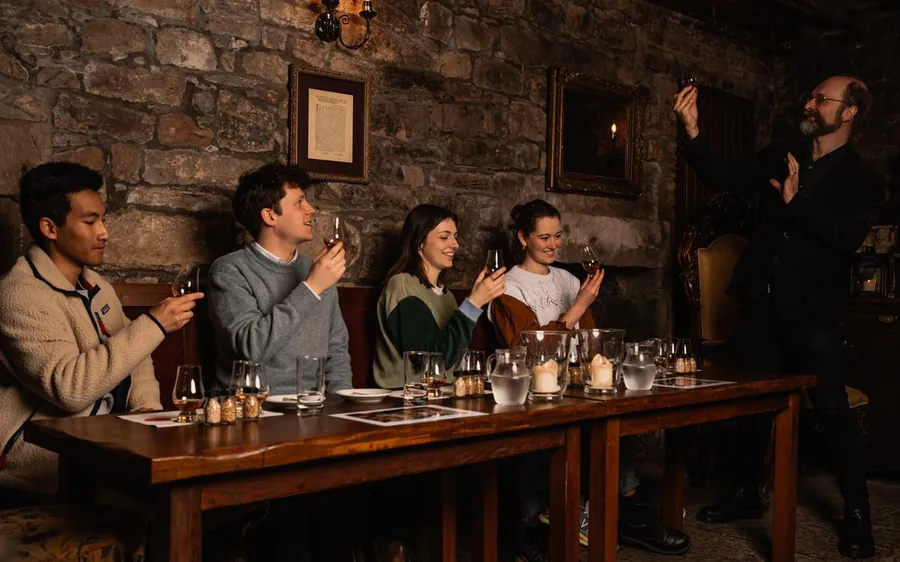 A small group at a whiskey tasting table with a guide talking