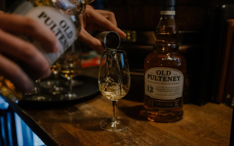 A wooden pub table set with whiskey glasses and a water jug